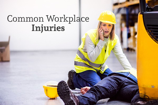 A female worker in a vest and hardhat kneels over an injured coworker who has been hit by a forklift, calling 911 beside the words "Common Workplace Injuries"