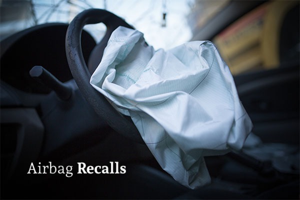A deflated front driver airbag in a car with the words airbag recalls