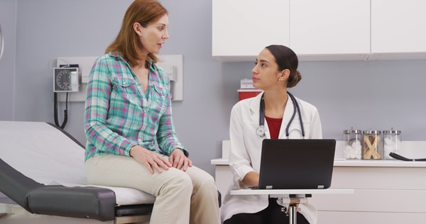 Médico que atiende a un paciente mientras usa una computadora portátil