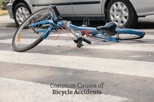 A mangled bike on a crosswalk beside a car above the words common causes of bicycle accidents