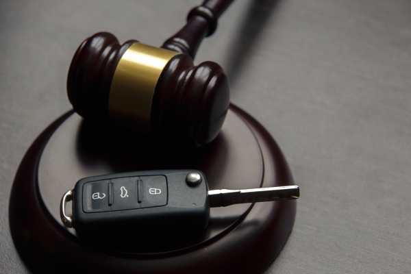 A gavel is sitting on a desk with a car key.