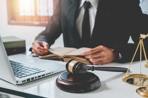 An attorney sitting at his desk with a gavel, legal scale, and computer.