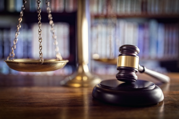 A gavel on a desk with a legal scale.