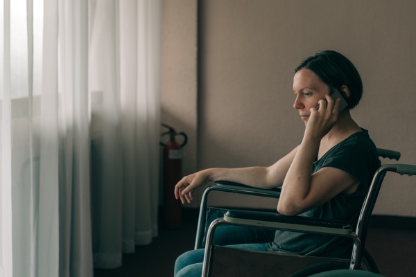 A woman in a wheel chair talking on the phone. 