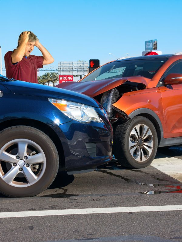 A car accident involving two cars and a man holding his head.